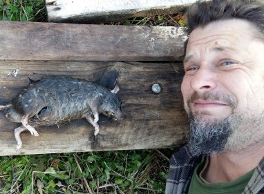 Dean 's face close to a very large dead rat. ew.